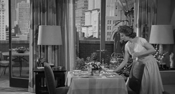 Movie still from “I'll Cry Tomorrow” (1955), directed by Daniel Mann – A woman standing at a table in front of a window; Wide shot, High angle