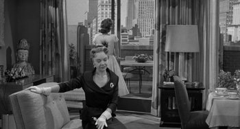 Movie still from “I'll Cry Tomorrow” (1955), directed by Daniel Mann – A woman in a black dress is sitting on a couch; Medium shot, Over the shoulder angle