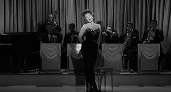 Movie still from “I'll Cry Tomorrow” (1955), directed by Daniel Mann – A black and white photo of a woman in front of an orchestra; Wide shot, Low angle