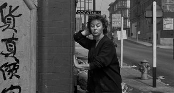 Movie still from “I'll Cry Tomorrow” (1955), directed by Daniel Mann – A woman standing next to a brick wall on the side of the street; Medium shot, Low angle