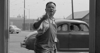 Movie still from “I'll Cry Tomorrow” (1955), directed by Daniel Mann – An old photo of a man in an apron directing traffic; Medium shot, Low angle