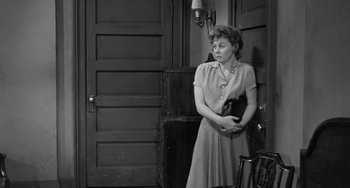 Movie still from “I'll Cry Tomorrow” (1955), directed by Daniel Mann – A woman standing in front of a door holding a purse; Medium shot, High angle