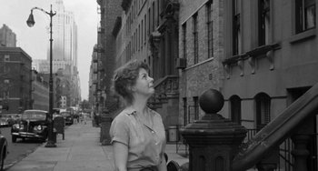 Movie still from “I'll Cry Tomorrow” (1955), directed by Daniel Mann – A black and white photo of a woman standing on the sidewalk; Medium shot, Low angle