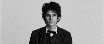 Movie still from “I'm Not There” (2007), directed by Todd Haynes – A black and white photo of a man wearing a suit and bow tie; Close Up shot, Low angle