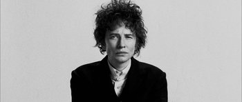 Movie still from “I'm Not There” (2007), directed by Todd Haynes – A black and white photo of a person with curly hair; Close Up shot, Low angle