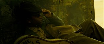 Movie still from “I'm Not There” (2007), directed by Todd Haynes – A man sitting on a couch with a backpack; Close Up shot, Overhead angle