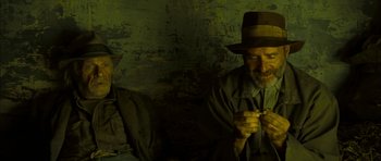 Movie still from “I'm Not There” (2007), directed by Todd Haynes – A man wearing a hat is sitting next to another man; Close Up shot, Low angle