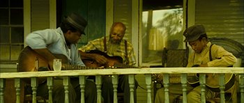 Movie still from “I'm Not There” (2007), directed by Todd Haynes – Two men sitting on a porch playing a guitar; Wide shot, Low angle