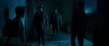 Movie still from “I'm Not There” (2007), directed by Todd Haynes – A group of men walking through a room at night; Wide shot, Low angle