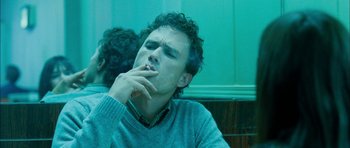 Movie still from “I'm Not There” (2007), directed by Todd Haynes – A man sitting in front of a green wall smoking a cigarette; Close Up shot, Low angle