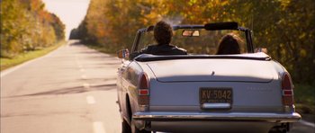 Movie still from “I'm Not There” (2007), directed by Todd Haynes – A man driving a car down a road; Wide shot, Over the shoulder angle