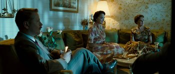 Movie still from “I'm Not There” (2007), directed by Todd Haynes – A woman sitting on a couch next to a man in a chair; Medium shot, Over the shoulder angle