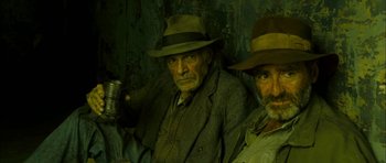 Movie still from “I'm Not There” (2007), directed by Todd Haynes – A man with a hat on and another man holding a can; Close Up shot, High angle
