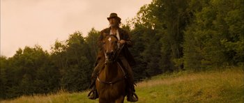Movie still from “I'm Not There” (2007), directed by Todd Haynes – A man riding on the back of a brown horse; Wide shot, Low angle