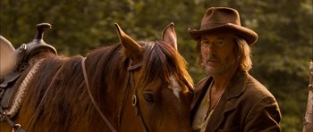 Movie still from “I'm Not There” (2007), directed by Todd Haynes – A man standing next to a brown horse; Close Up shot, Over the shoulder angle