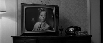 Movie still from “I'm Not There” (2007), directed by Todd Haynes – An old tv with a man on the screen and an old phone on the table; Close Up shot, Over the shoulder angle