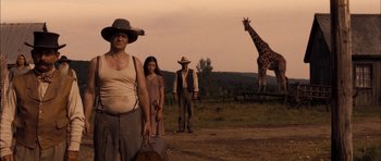 Movie still from “I'm Not There” (2007), directed by Todd Haynes – A group of people standing next to a giraffe; Wide shot, Low angle