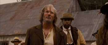 Movie still from “I'm Not There” (2007), directed by Todd Haynes – A man with long hair and a beard standing next to a man with a hat; Close Up shot, Low angle