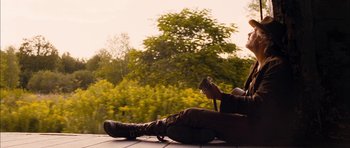 Movie still from “I'm Not There” (2007), directed by Todd Haynes – A man sitting on the ground holding a guitar; Wide shot, Low angle