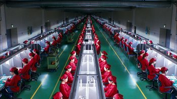 Movie still from “I'm a Cyborg, But That's OK” (2006), directed by Park Chan-wook – Rows of red chairs in a factory with rows of desks in front of them; Extreme Wide shot, Overhead angle