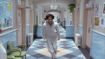 Movie still from “I'm a Cyborg, But That's OK” (2006), directed by Park Chan-wook – A man in a white suit walking down a hall way; Wide shot, High angle
