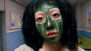 Movie still from “I'm a Cyborg, But That's OK” (2006), directed by Park Chan-wook – A woman with a green face mask on; Close Up shot, Overhead angle