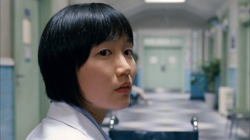 Movie still from “I'm a Cyborg, But That's OK” (2006), directed by Park Chan-wook – A young woman in a white lab coat is looking at the camera; Close Up shot, Over the shoulder angle