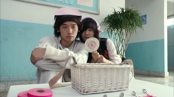 Movie still from “I'm a Cyborg, But That's OK” (2006), directed by Park Chan-wook – A man and a woman sitting in front of a wicker basket; Medium shot, Over the shoulder angle