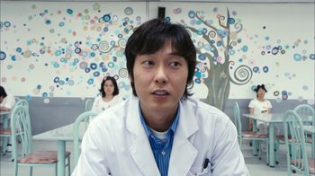 Movie still from “I'm a Cyborg, But That's OK” (2006), directed by Park Chan-wook – A man in a white lab coat sitting next to a woman; Medium shot, Low angle