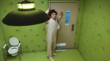 Movie still from “I'm a Cyborg, But That's OK” (2006), directed by Park Chan-wook – A man standing in front of a door in a room; Wide shot, High angle