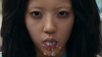 Movie still from “I'm a Cyborg, But That's OK” (2006), directed by Park Chan-wook – A young woman with a mouth full of sugar; Extreme Close Up shot, Overhead angle