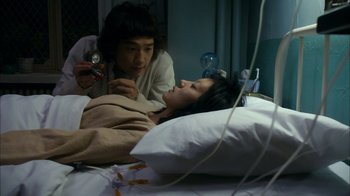Movie still from “I'm a Cyborg, But That's OK” (2006), directed by Park Chan-wook – A woman laying in a hospital bed while another woman takes a picture of it; Medium shot, High angle