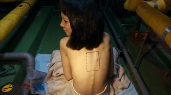 Movie still from “I'm a Cyborg, But That's OK” (2006), directed by Park Chan-wook – A woman sitting on the ground with a piece of paper on her back; Medium shot, Overhead angle