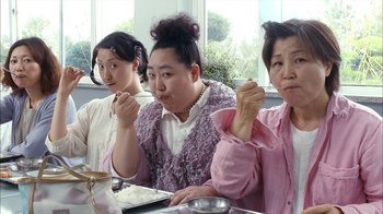 Movie still from “I'm a Cyborg, But That's OK” (2006), directed by Park Chan-wook – A group of people sitting at a table eating food; Medium shot, Low angle
