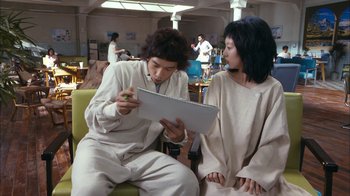 Movie still from “I'm a Cyborg, But That's OK” (2006), directed by Park Chan-wook – A man and a woman sitting on a couch looking at a notebook; Medium shot, Over the shoulder angle