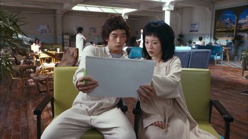 Movie still from “I'm a Cyborg, But That's OK” (2006), directed by Park Chan-wook – A man and a woman sitting on a couch looking at a notebook; Medium shot, Over the shoulder angle