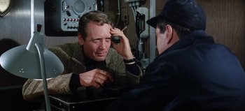 Movie still from “Ice Station Zebra” (1968), directed by John Sturges – A man sitting in front of another man holding a cigarette; Close Up shot, Over the shoulder angle