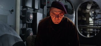 Movie still from “Ice Station Zebra” (1968), directed by John Sturges – An older man wearing a purple hat and a brown jacket; Medium shot, Low angle