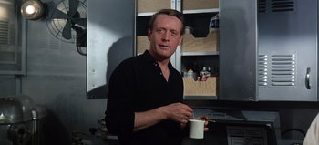 Movie still from “Ice Station Zebra” (1968), directed by John Sturges – A man holding a coffee cup in a kitchen; Close Up shot, Low angle