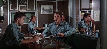 Movie still from “Ice Station Zebra” (1968), directed by John Sturges – A group of men sitting at a table in a restaurant; Medium shot, Low angle
