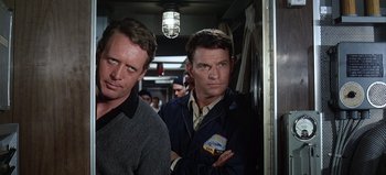 Movie still from “Ice Station Zebra” (1968), directed by John Sturges – A couple of men standing next to each other on a train; Medium shot, Low angle