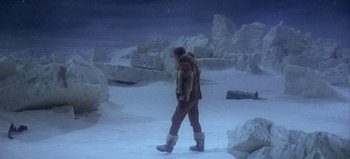 Movie still from “Ice Station Zebra” (1968), directed by John Sturges – A man walking in the snow wearing snow boots; Wide shot, High angle