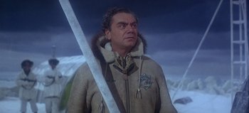 Movie still from “Ice Station Zebra” (1968), directed by John Sturges – A man wearing a fur coat and holding a sword; Medium shot, Low angle