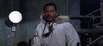 Movie still from “Ice Station Zebra” (1968), directed by John Sturges – A man in a white parka is standing in front of a window; Close Up shot, Low angle