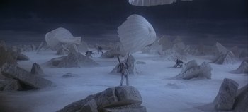 Movie still from “Ice Station Zebra” (1968), directed by John Sturges – A man holding a parachute in the middle of the desert; Extreme Wide shot, High angle