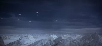 Movie still from “Ice Station Zebra” (1968), directed by John Sturges – Several parachutes are flying in the sky over a snowy landscape; Extreme Wide shot, High angle