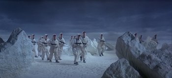 Movie still from “Ice Station Zebra” (1968), directed by John Sturges – A group of men in white suits walking across a snow covered field; Wide shot, High angle
