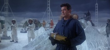 Movie still from “Ice Station Zebra” (1968), directed by John Sturges – A man in a blue parka holding a yellow object in his hand; Medium shot, Low angle