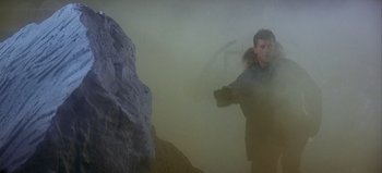 Movie still from “Ice Station Zebra” (1968), directed by John Sturges – A man standing in front of a large rock in the fog; Wide shot, Low angle