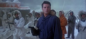 Movie still from “Ice Station Zebra” (1968), directed by John Sturges – A man holding a handgun while standing in front of a group of people; Medium shot, Low angle